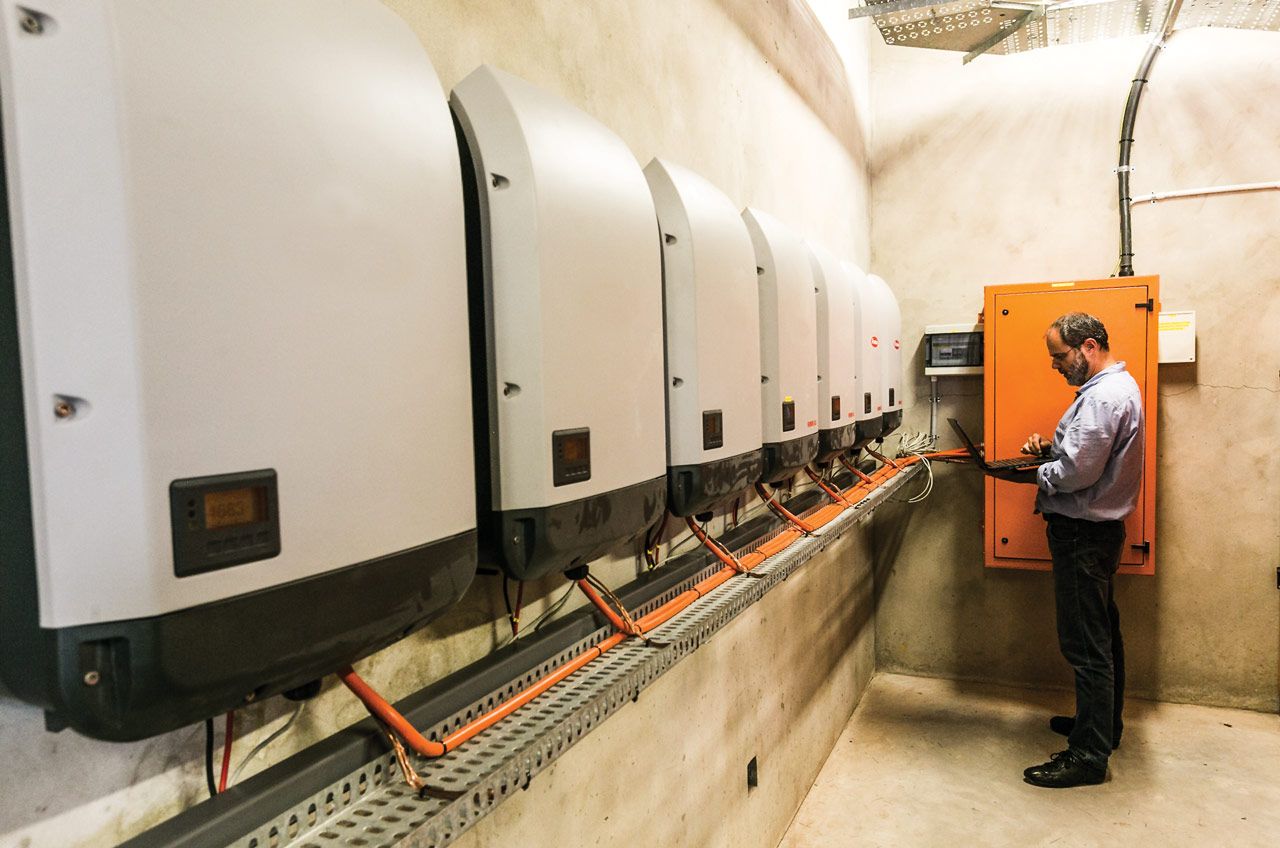 Engineer inspecting inverter setting of 200kVA Fronius grid-tied inverter at Thembalethu Mall, George, Garden Route installation